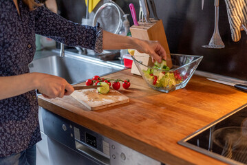 person preparing food in kitchen, person cutting vegetables in kitchen