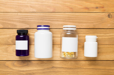 Plastic bottles with vitamins on wooden background, top view