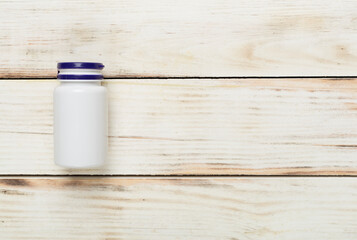 Plastic bottle with vitamins on wooden background, top view