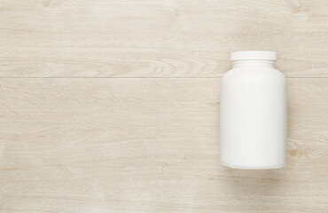 Plastic bottle with vitamins on wooden background, top view