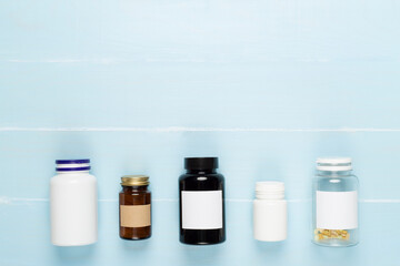 Plastic bottles with vitamins on wooden background, top view