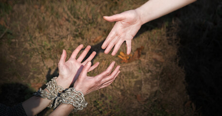 Bound hands reach out to the outstretched hand for help