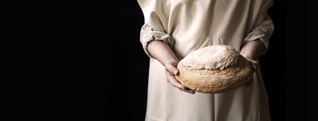 Hands holding bread on black background