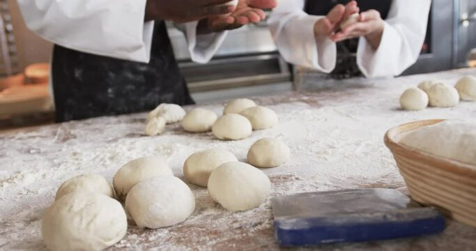 Diverse bakers working in bakery kitchen, making rolls from dough in slow motion
