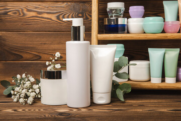 Tubes with cream on the background of a brown tabletop in the bathroom. Shelf with cosmetics. Face and body skin care. Moisturizer, toner and serum. Beauty concept. Place for text. Copy space.