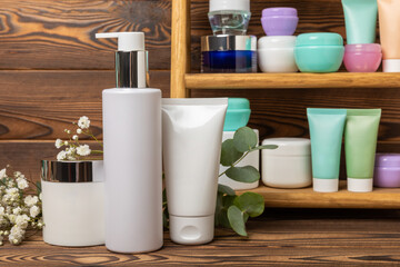 Tubes with cream on the background of a brown tabletop in the bathroom. Shelf with cosmetics. Face and body skin care. Moisturizer, toner and serum. Beauty concept. Place for text. Copy space.