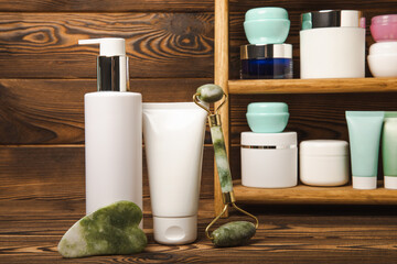 Tubes with cream on the background of a brown tabletop in the bathroom. Shelf with cosmetics. Face and body skin care. Moisturizer, toner and serum. Beauty concept. Place for text. Copy space.