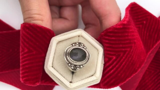 Unique labradorite crystal silver ring in a woman's hand on a white background, vintage jewelry concept, promotional video for an online jewelry store
