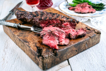 Traditional wagyu entrecote beef steak with green asparagus and red wine served on an old rustic wooden board
