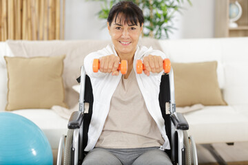 portrait of senior woman in wheelchair lifting dumbbells