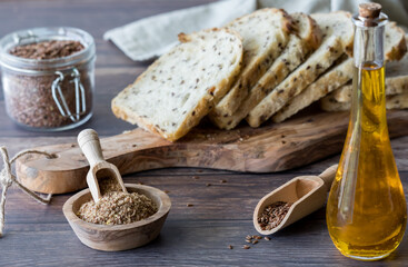 Fototapeta na wymiar Flax seed bread surrounded by whole and ground flax seeds and flax seed oil.