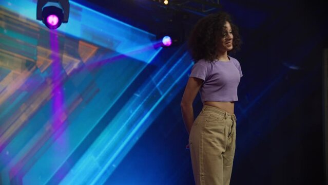 Young female woman girl dancer talent is standing on stage, talking to the judges during audition. Recording of television style broadcast talent show