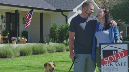 Homeowners stand in front of their new house with dog and children in background