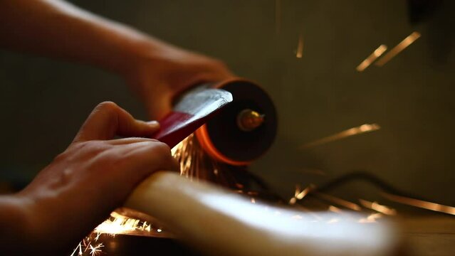 sharpClose-up of men's hands sharpening an axe on an electric sharpener. Repair of home tools. 
Sparks fly.