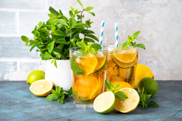 Iced tea with ingredients. Black tea with lemon, lime, mint and ice. Cold lemonade, summer drink at kitchen table.