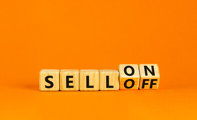 Sell on or off symbol. Businessman turns wooden cubes and changes word Sell off to Sell on. Beautiful orange table orange background. Business and sell on or off concept. Copy space.