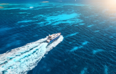 Aerial view of fast floating yacht on blue sea at sunny day in summer. Travel in Sardinia, Italy....