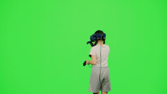 Little girl design artist VR headset drawing picture in virtual reality creativity game. The child in virtual reality paint imagination picture on chroma key green screen. Concept VR art design game