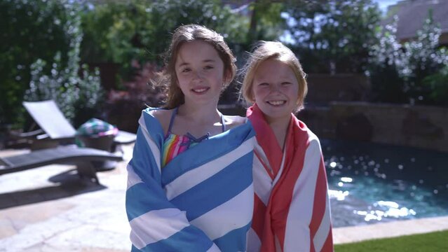 Portrait of two girls at the pool wrapped in beach towels