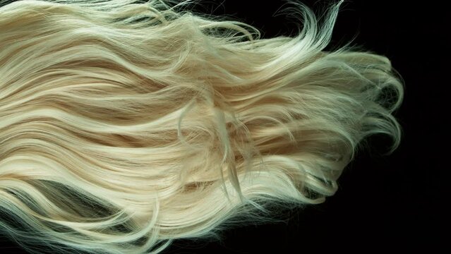 Super slow motion of wavy blonde hair in detail. Filmed on high speed cinema camera, 1000 fps. Isolated on black background.