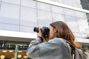 Close up shot of female photographer. Young redhead. Taking photos with professional camera in hand. Face in viewfinder.