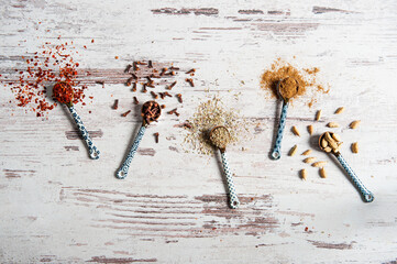 Top view of scattered spices in hand painted blue and white ceramic spoons on weathered white...