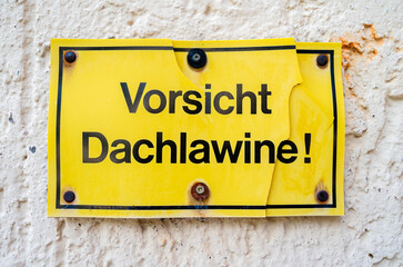 A sign on the wall warning in German about snow falling from the roof. English translation: Caution, roof avalanche