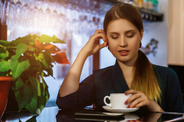 Thoughtful emotion of cover woman actress in black sitting posing at table in restaurant, pensive...