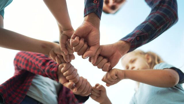 Team of people together in nature. Unity and commonwealth family happiness. Hands in the form of punches are a symbol of teamwork. Family friendship together in nature. Business cooperation concept.