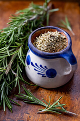 Fresh and dry rosemary placed in a ceramic glass on a wooden board .viewed from above