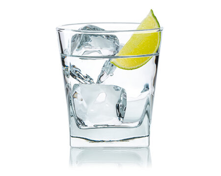 Glass of water with ice cubes and  fresh lime slice. Cold lemonade. Frozen water in shape of cube. Ice for lime drink, lemon soda or cocktails. Natural or real ice cubes. White Isolated background