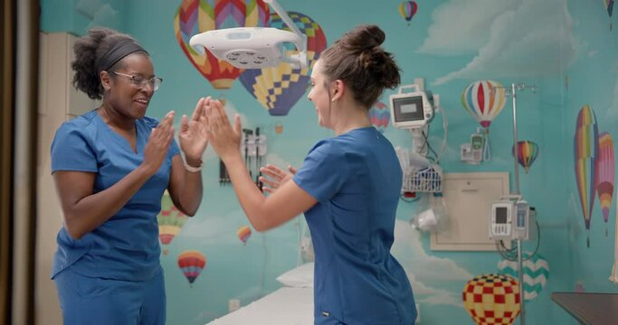 Female nurses play a hand clapping game in a children's hospital room