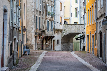 Picturesque alley with old stone houses and arched bridge in the medieval city of Pau, France.