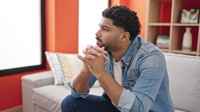 African american man sitting on sofa with serious expression at home