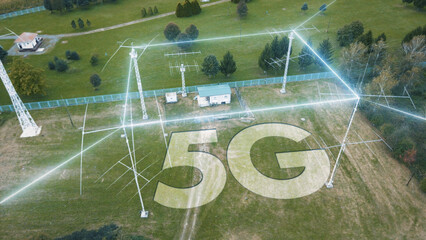 5G lettering on a green area surrounded by communications antennas sending out signals. Fast speed wireless internet network mobile technology concept.