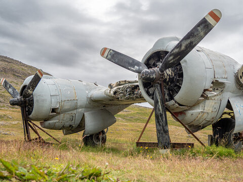 A fragment of airplane wing with three-bladed aircraft propeller against cloudy sky