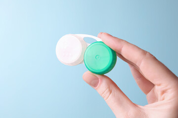 Contact lens container in hand on a colored background. Vision correction. 