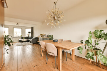 a dining room with wood flooring and a chandel in the center of the room is an open living area