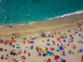 aerial view from the Caribbean sea drone of Tropea with its beach crowded with tourists with their colorful umbrellas. We are in Calabria Italy