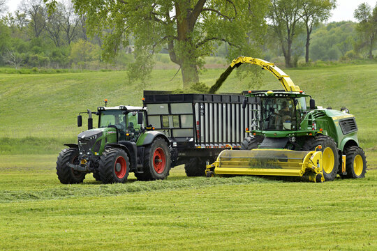 WAUPON; WISCONSIN - May 16, 2023: John Deere 9900 forage harvester loading silage into a Boss wagon being pulled by a Fendt tractor