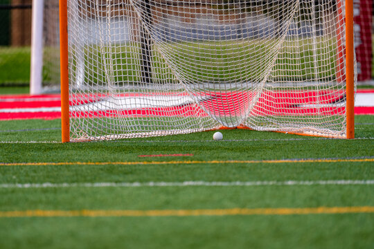Dramatic late afternoon photo of a lacrosse goal on a synthetic turf field.	