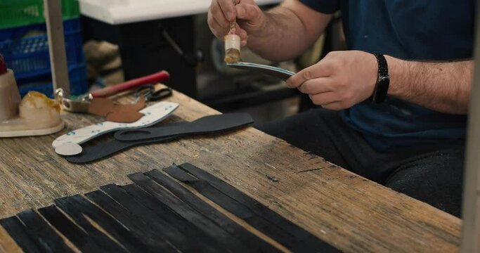 Close-up shot, the hands of a man who glues parts of the insoles for shoes. Shoe production at a special handmade factory