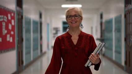 Slow motion closeup portrait of smiling happy woman teacher walking down an empty school hallway.