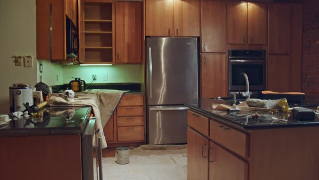 Wide angle of a kitchen under construction with tarps, tools and paint cans