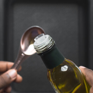 Pouring olive oil into a measuring spoon, measuring a tablespoon of oil