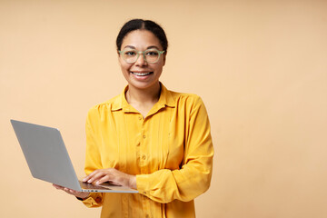 Beautiful smiling African American business woman holding laptop working online