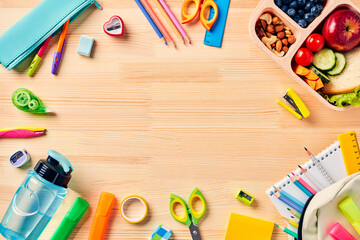 Frame of school supplies, backpack, kids lunch box on wooden table. Top view. Flat lay.