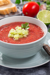 Gazpacho soup garnished with cucumber and cilantro, in bowl, vertical closeup