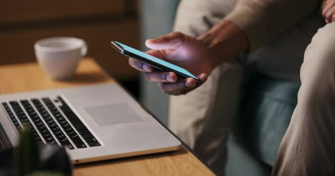 Close-up: An African American man chuckles at a hilarious viral video, finding a moment of lighthearted joy on his cell phone.