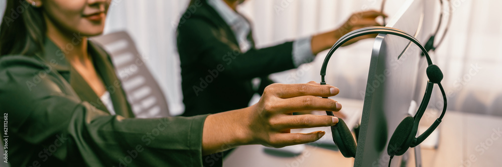 Aufkleber panorama focus hand holding headset on call center workspace desk with blur background of operator t